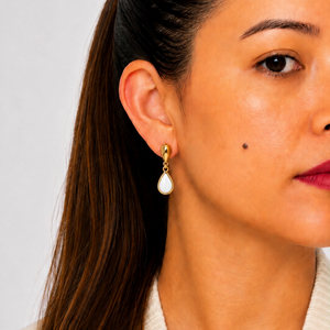 Close-up of a woman wearing a mother pearl earring against a neutral background