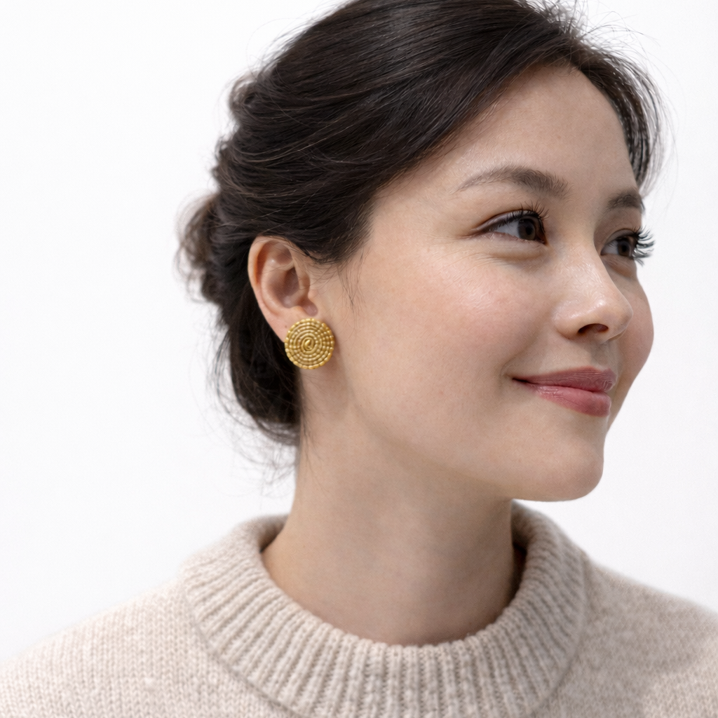 Woman wearing golden grass  earrings with a plain background Capim dourado
