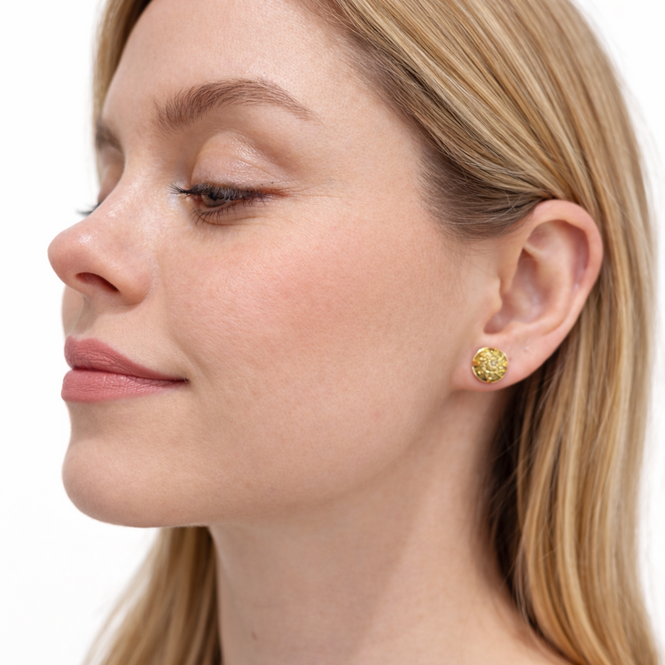 Close-up of a woman wearing a capim dourado earring on a white background