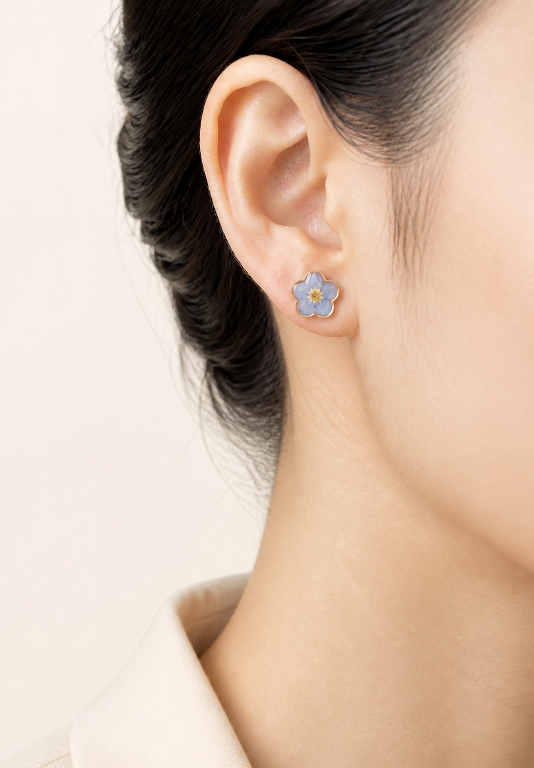 Blue forget-me-not resin stud earrings worn on the ear