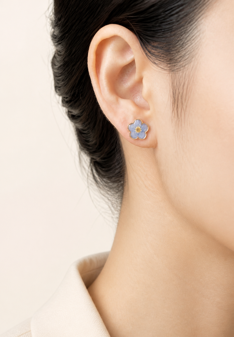 Blue forget-me-not resin stud earrings worn on the ear
