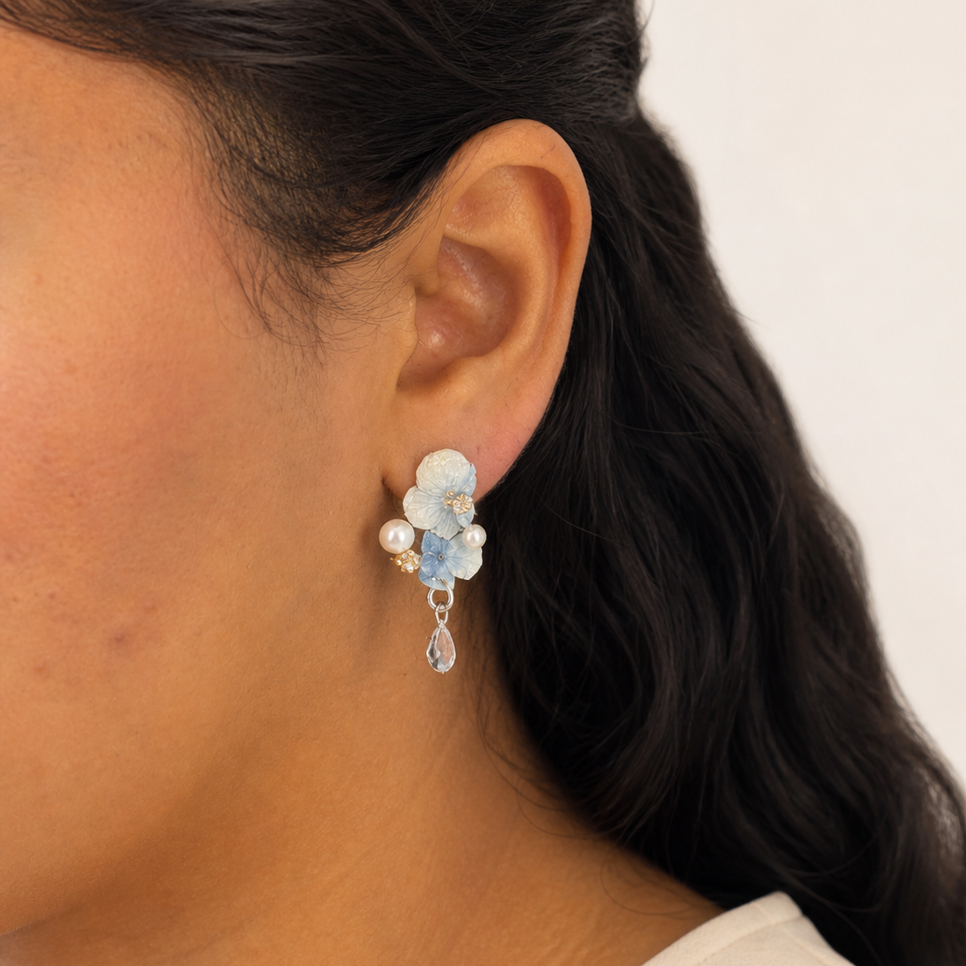 Blue hydrangea pearl drop earrings worn on the ear