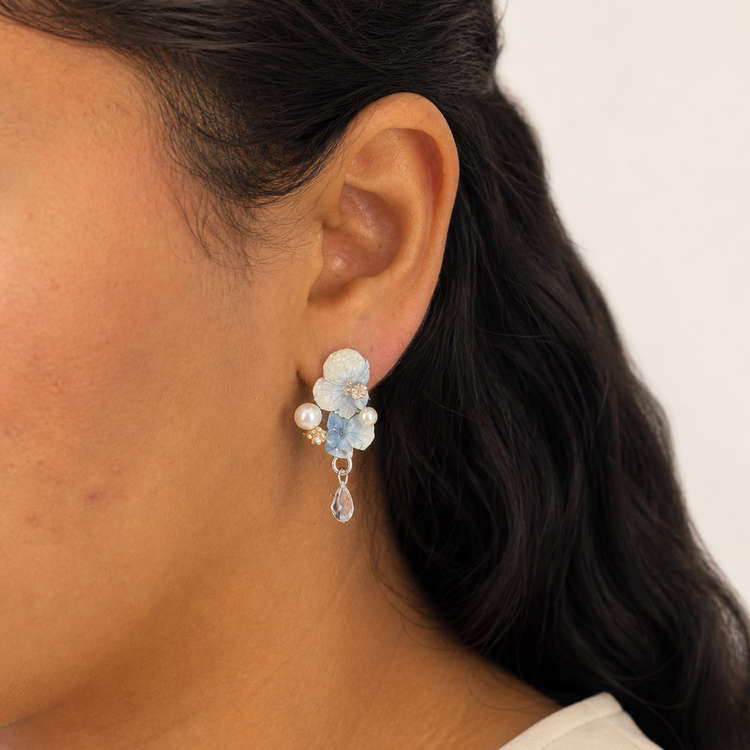 Blue hydrangea pearl drop earrings worn on the ear